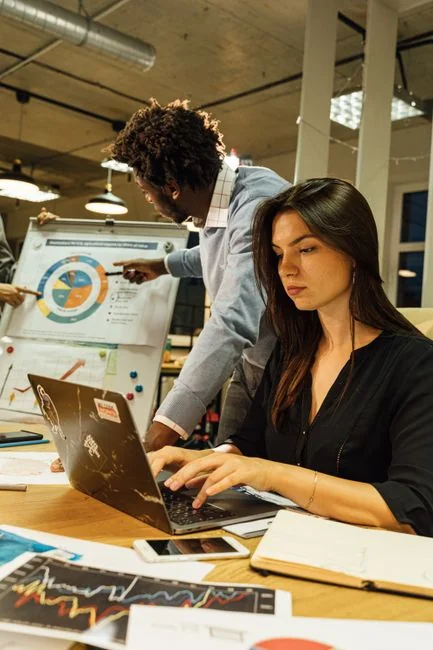 A modern workspace showing hands analyzing marketing data on a laptop and paper documents.